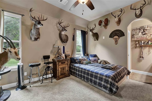 carpeted bedroom with ceiling fan and multiple windows