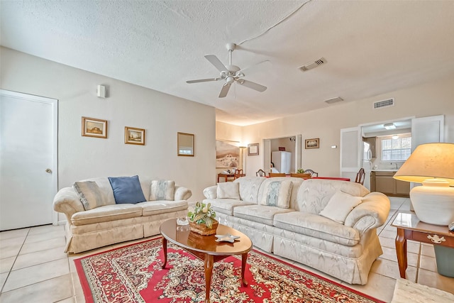 tiled living room featuring ceiling fan and a textured ceiling