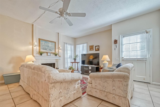 living room with a textured ceiling, ceiling fan, and light tile patterned floors