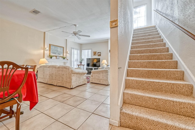 stairway with ceiling fan and tile patterned flooring