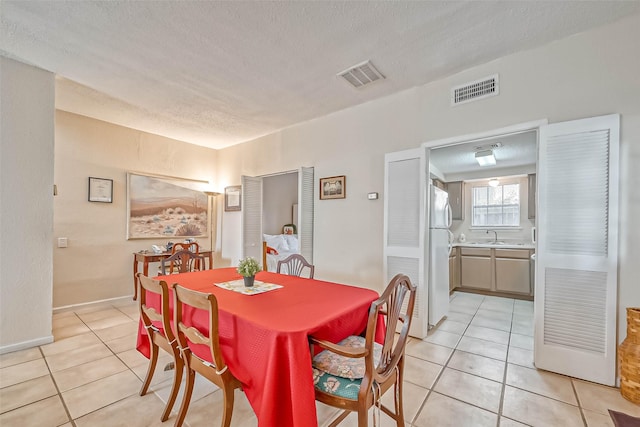 dining room with sink, a textured ceiling, and light tile patterned floors