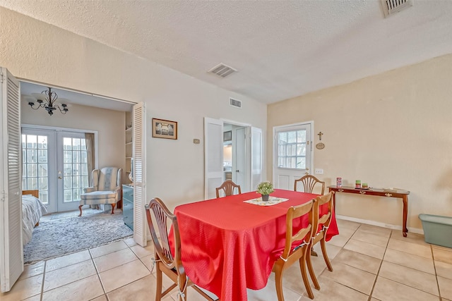 tiled dining room with a textured ceiling, plenty of natural light, french doors, and a notable chandelier