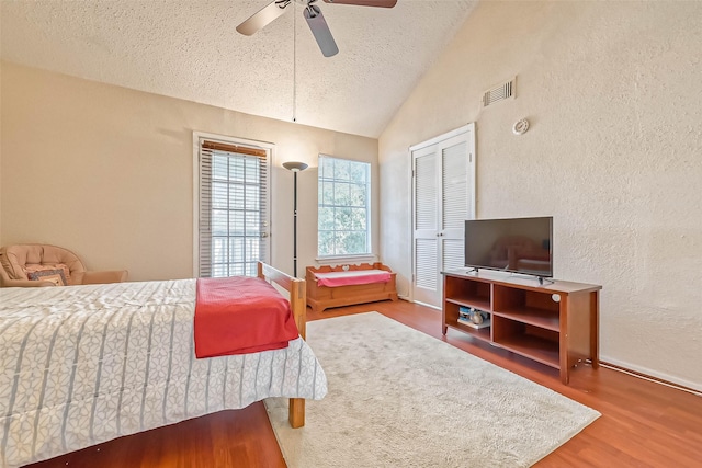 bedroom featuring a textured ceiling, hardwood / wood-style flooring, a closet, vaulted ceiling, and ceiling fan