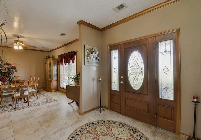 tiled entryway featuring ceiling fan, ornamental molding, and a textured ceiling