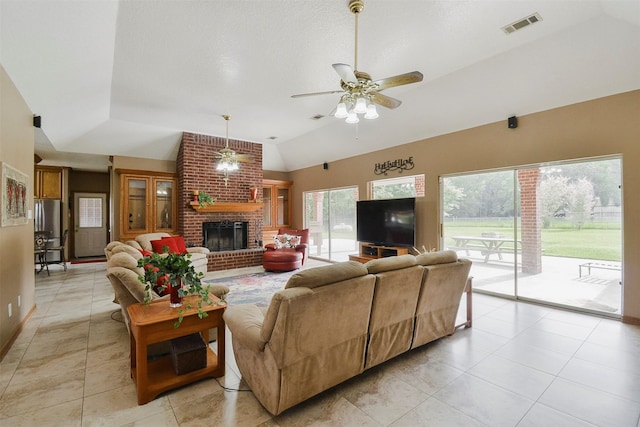 tiled living room with ceiling fan, brick wall, a brick fireplace, and vaulted ceiling