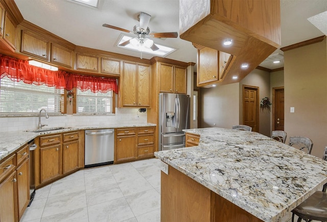 kitchen featuring backsplash, ceiling fan, a kitchen bar, sink, and stainless steel appliances