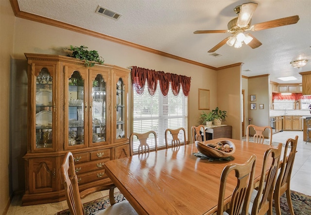 dining room featuring light tile floors, sink, ceiling fan, a textured ceiling, and ornamental molding