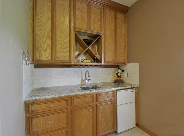 kitchen featuring light stone counters, backsplash, dishwasher, and sink