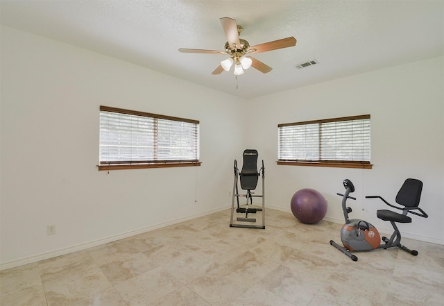 workout area with ceiling fan, light tile flooring, and a healthy amount of sunlight