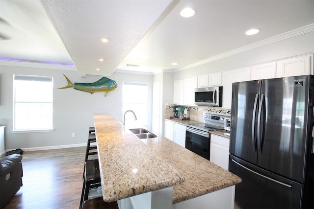 kitchen with white cabinets, dark hardwood / wood-style floors, an island with sink, stainless steel appliances, and sink