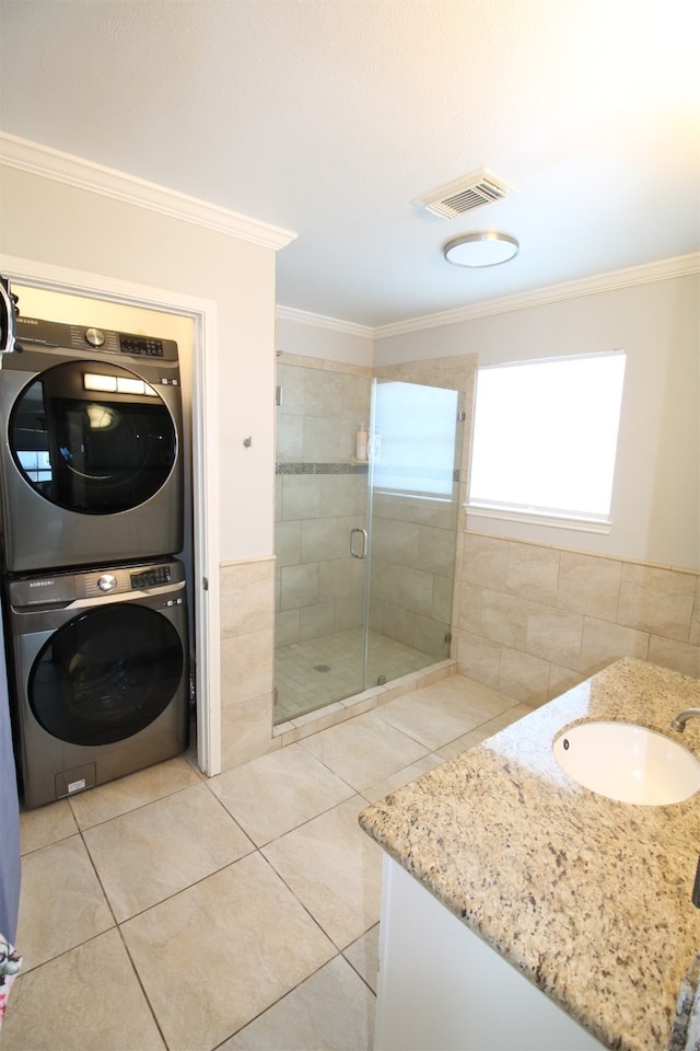 bathroom featuring stacked washing maching and dryer, ornamental molding, and sink