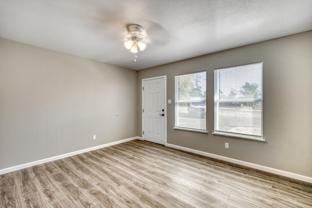 spare room featuring light hardwood / wood-style floors, ceiling fan, and a textured ceiling