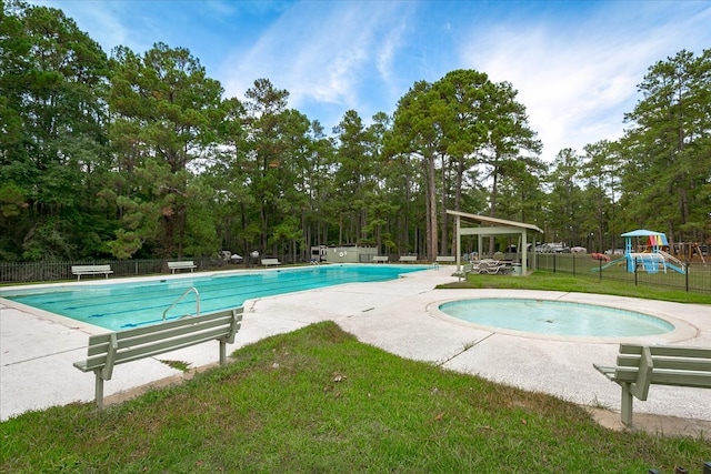 view of pool featuring a lawn, a playground, and a patio area