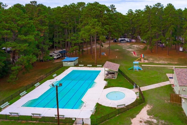 view of pool with a yard, an outdoor structure, and a hot tub