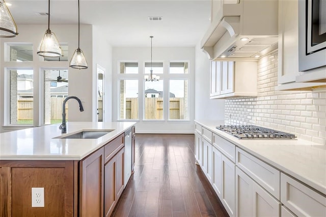 kitchen with pendant lighting, tasteful backsplash, dark wood-type flooring, and sink