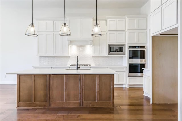 kitchen featuring an island with sink, pendant lighting, stainless steel appliances, white cabinets, and dark hardwood / wood-style flooring