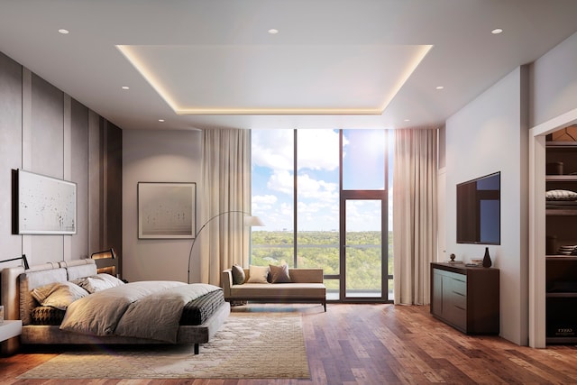 bedroom with a wall of windows, hardwood / wood-style floors, and a tray ceiling