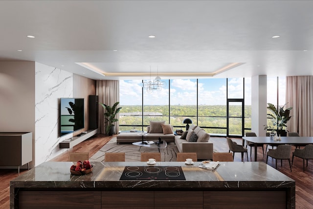 living room featuring an inviting chandelier, a raised ceiling, dark hardwood / wood-style flooring, and a wall of windows