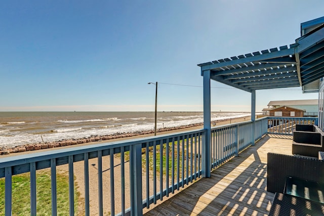 wooden terrace with a water view, a pergola, and a beach view