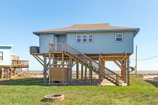 rear view of property with a wooden deck, a fire pit, and a yard