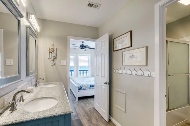 bathroom featuring ceiling fan, double sink, vanity with extensive cabinet space, and wood-type flooring