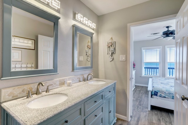 bathroom featuring ceiling fan, dual sinks, large vanity, and wood-type flooring