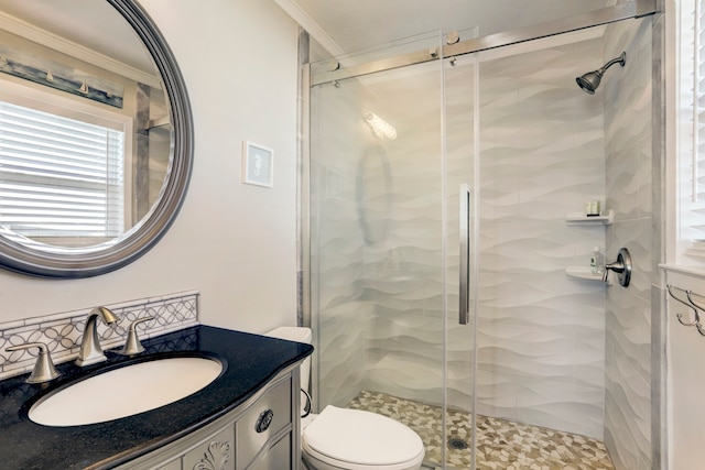 bathroom featuring crown molding, toilet, vanity, and a shower with door