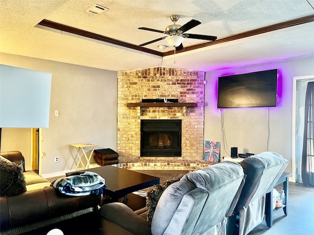 living room with a textured ceiling, ceiling fan, and a brick fireplace