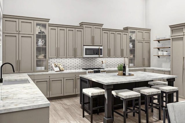 kitchen with backsplash, a kitchen bar, sink, light wood-type flooring, and a kitchen island