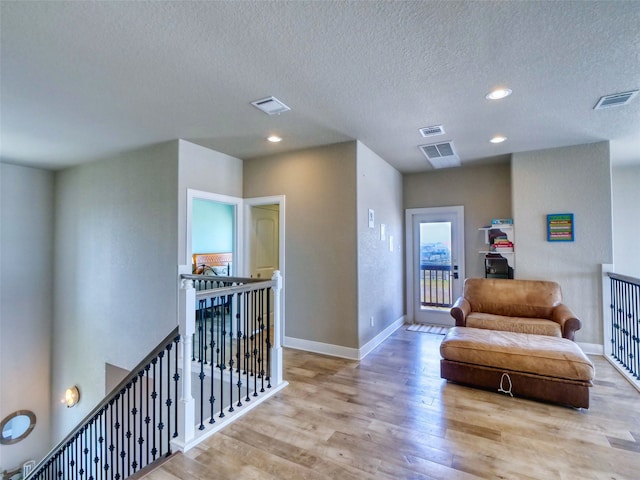 sitting room with a textured ceiling and light hardwood / wood-style flooring