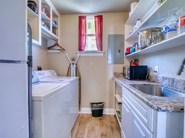 laundry area with a textured ceiling, separate washer and dryer, sink, and light hardwood / wood-style flooring