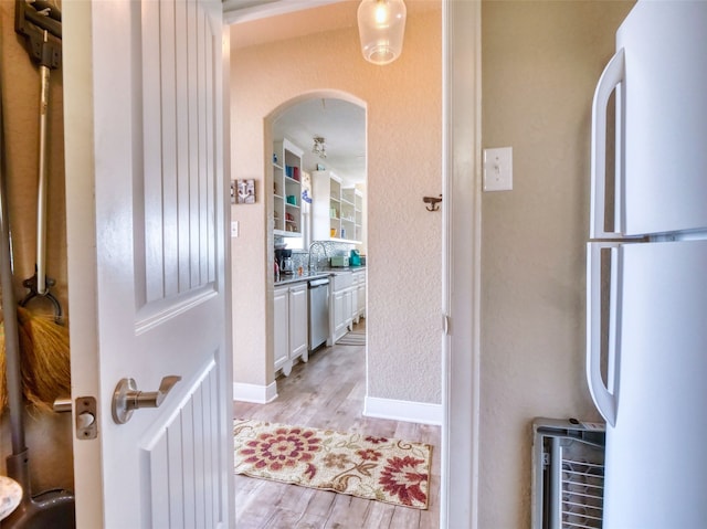 interior space with white refrigerator, light hardwood / wood-style floors, white cabinets, and stainless steel dishwasher