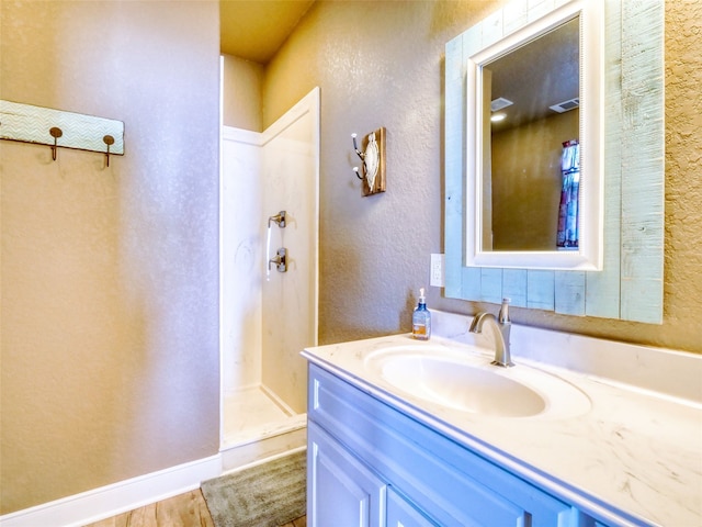 bathroom featuring wood-type flooring, walk in shower, and vanity with extensive cabinet space