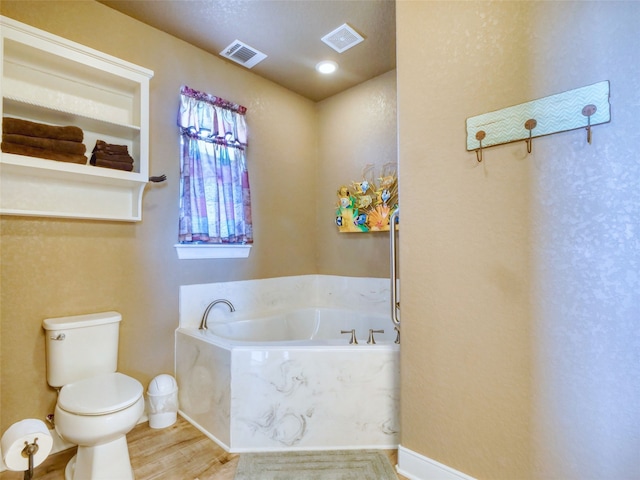 bathroom with wood-type flooring, toilet, and a bath to relax in