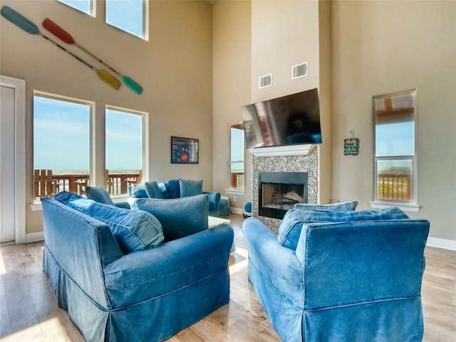 living room featuring light hardwood / wood-style flooring, high vaulted ceiling, and a fireplace