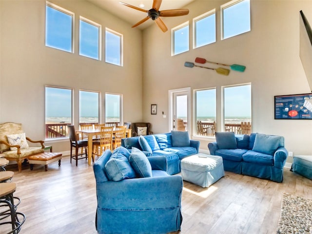 living room featuring a high ceiling, light hardwood / wood-style floors, and ceiling fan