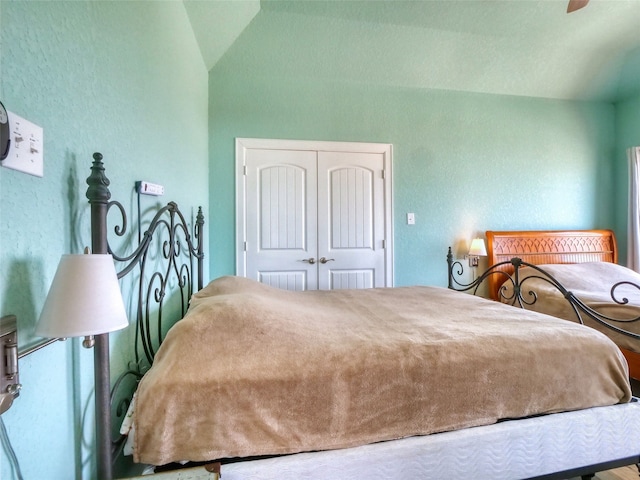 bedroom with ceiling fan, lofted ceiling, and a closet