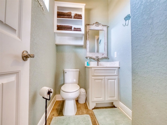 bathroom with vanity, toilet, and hardwood / wood-style floors