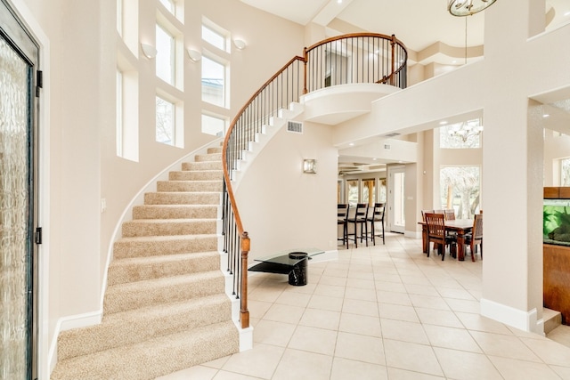 stairs with an inviting chandelier, light tile floors, and a high ceiling