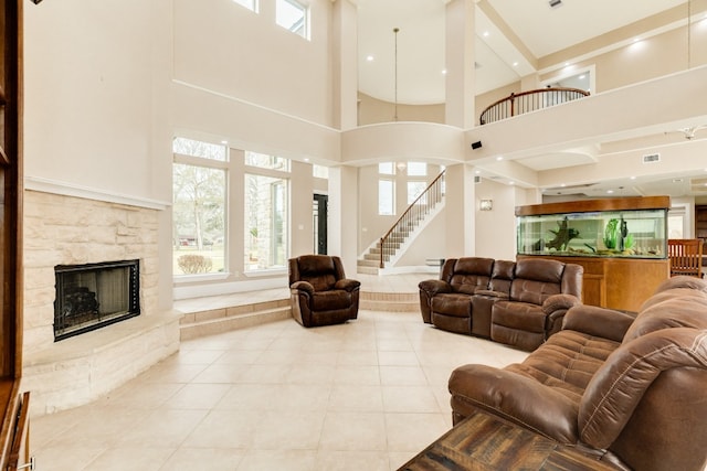 living room with a stone fireplace, light tile floors, and a towering ceiling