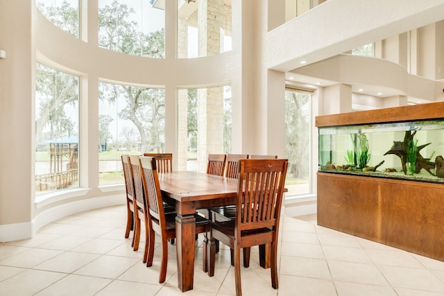 dining space with light tile flooring, a wealth of natural light, and a high ceiling