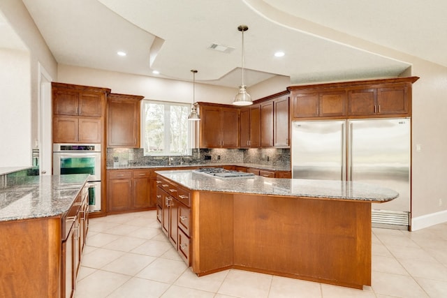 kitchen with tasteful backsplash, a kitchen island, appliances with stainless steel finishes, and light stone counters