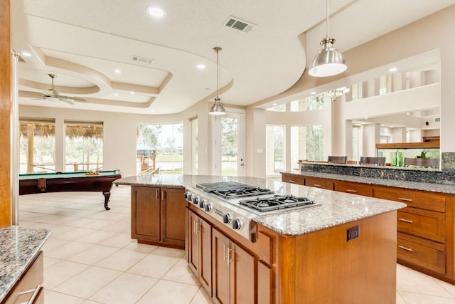 kitchen with billiards, hanging light fixtures, a tray ceiling, and a kitchen island