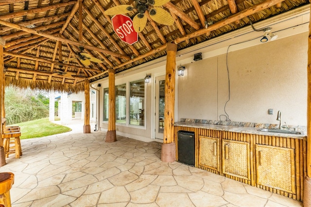 view of patio with exterior kitchen, ceiling fan, a gazebo, and an outdoor wet bar