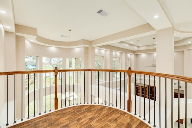 corridor with a tray ceiling and hardwood / wood-style flooring