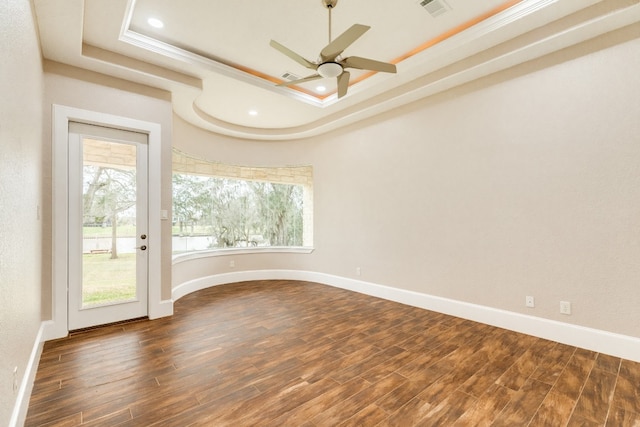 empty room featuring plenty of natural light, a tray ceiling, ceiling fan, and dark hardwood / wood-style flooring