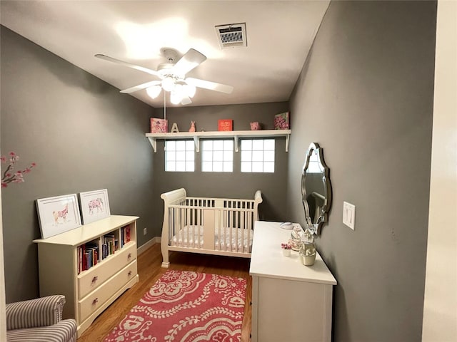 9822 Samantha Suzanne Ct, Houston, TX 77025 - bedroom featuring a nursery area, ceiling fan, and dark wood-type flooring