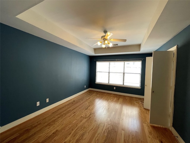 9822 Samantha Suzanne Ct, Houston, TX 77025 - empty room featuring ceiling fan, a tray ceiling, and light hardwood / wood-style flooring