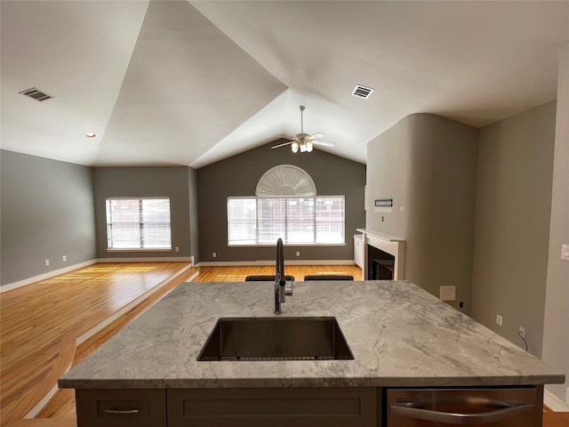 9822 Samantha Suzanne Ct, Houston, TX 77025 - kitchen featuring light stone countertops, ceiling fan, light hardwood / wood-style flooring, a kitchen island with sink, and sink