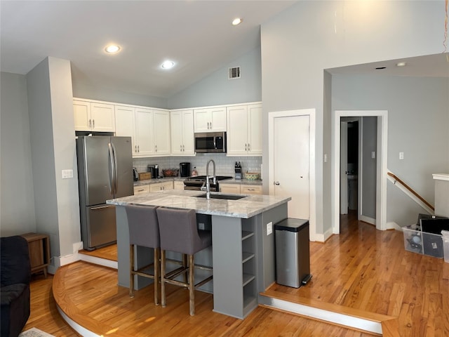 9822 Samantha Suzanne Ct, Houston, TX 77025 - kitchen with white cabinetry, light hardwood / wood-style flooring, appliances with stainless steel finishes, and light stone counters